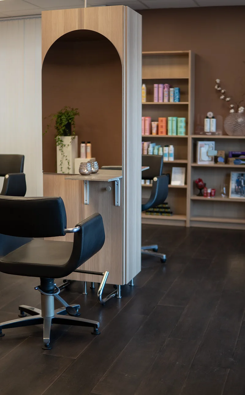 Salongens ljusa inredning med frisörstolar, speglar och hyllor med hårvård